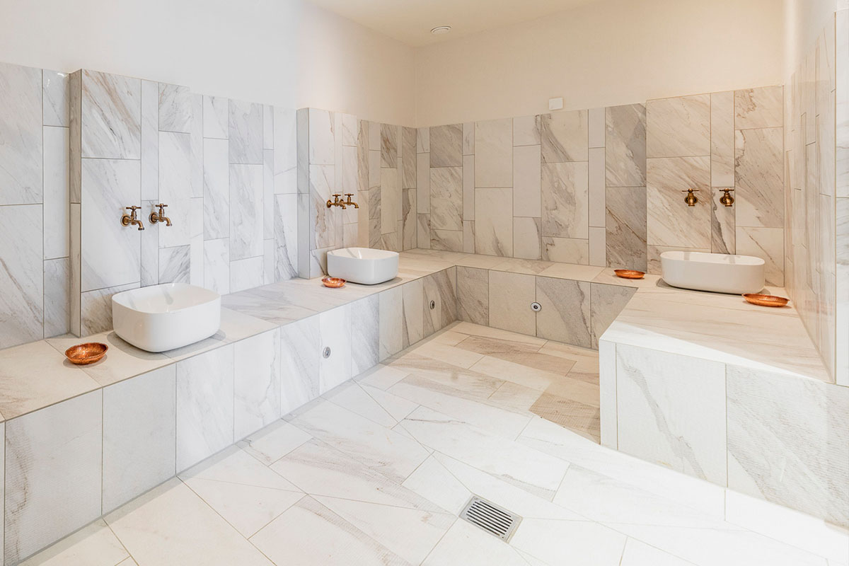 Schönes helles Badezimmer mit drei Waschbecken im arborea Marina Resort Neustadt.
