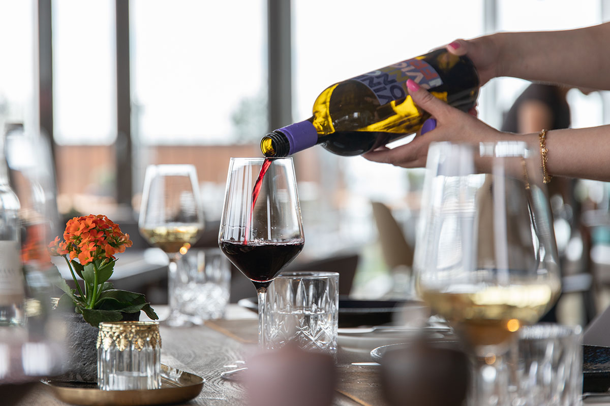 Rotwein wird in ein Weinglas eingeschenkt in der Kutter Kitchen im arborea Marina Resort Neustadt.