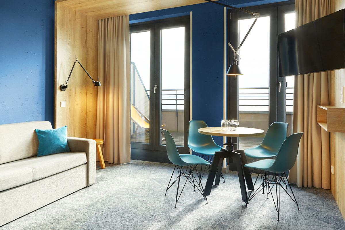 Der Wohnbereich mit Couch, kleinem Esstisch mit Stühlen und TV in der arborea Junior Suite im arborea Marina Resort Neustadt.