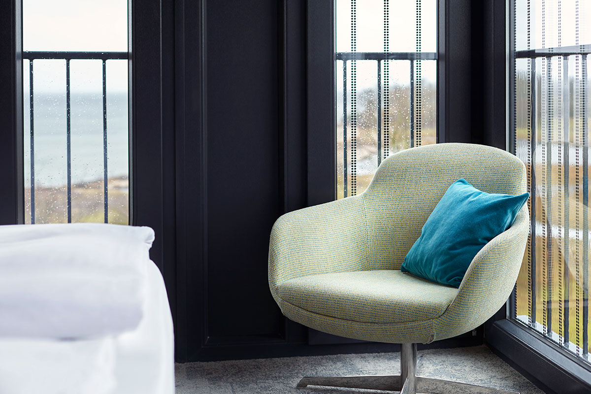 Gemütlicher Sessel mit einem blauen Kissen im Doppelzimmer Landblick im arborea Marina Resort Neustadt.