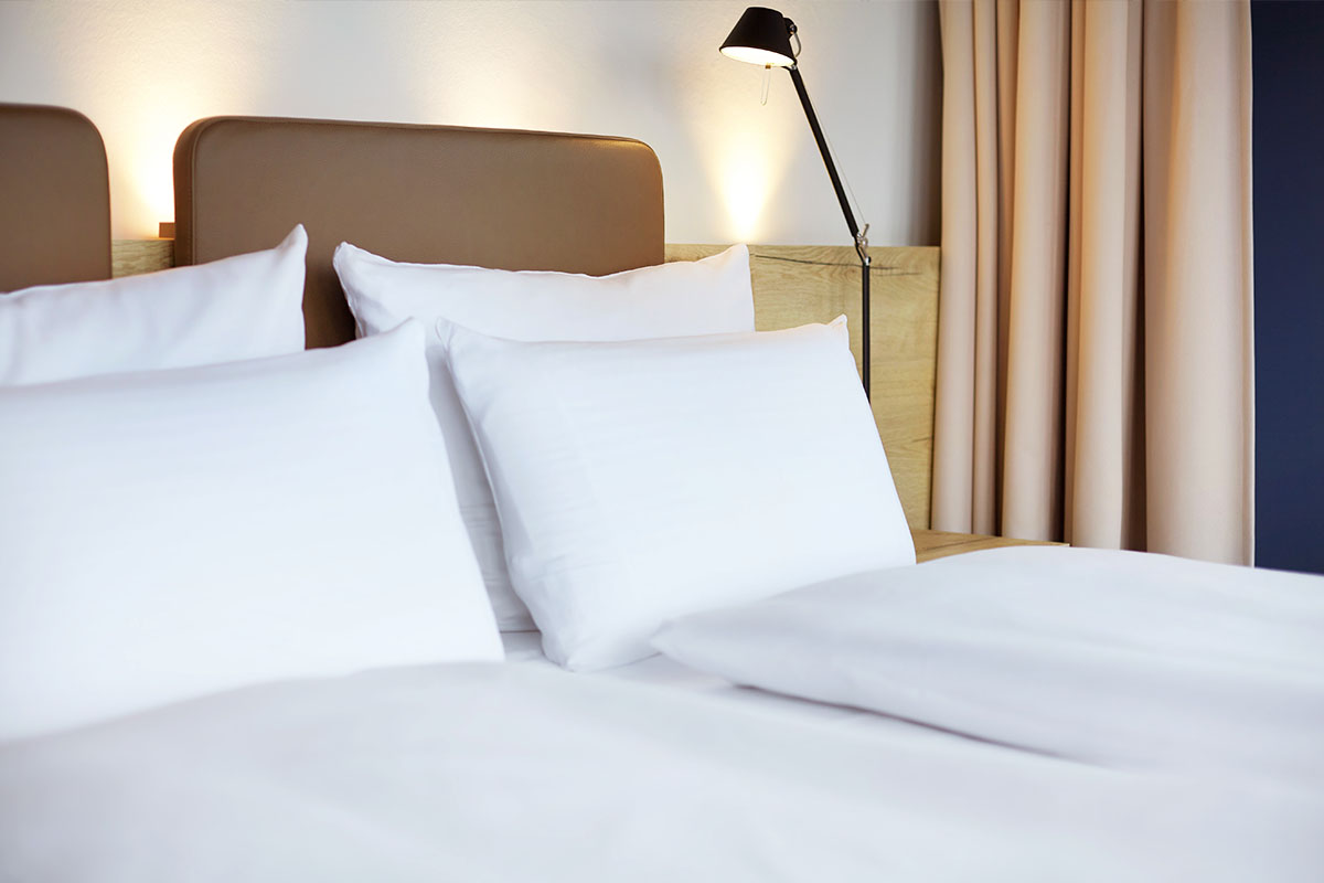 Der Kopfbereich des Kingsize Doppelbettes mit gemütlichen Kissen im Doppelzimmer Landblick im arborea Marina Resort Neustadt.